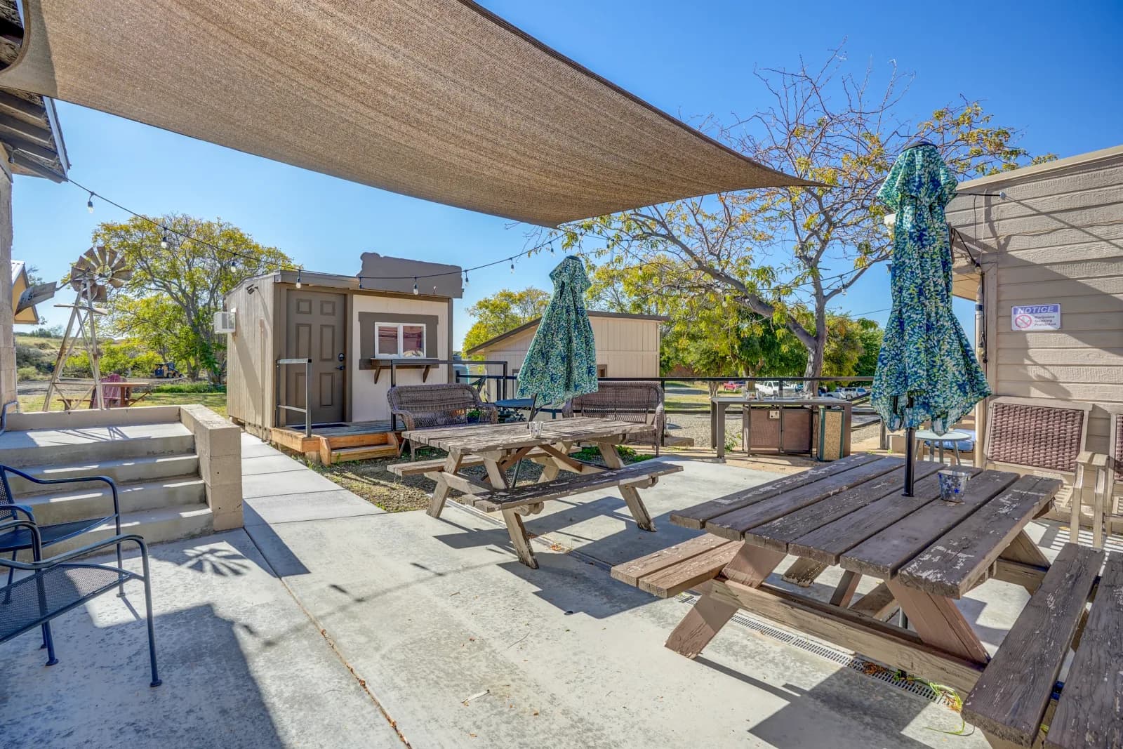 Wide view of the shared patio, picnic tables, and shade sail